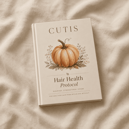 A hardcover book titled 'CUTIS Hair Health Protocol' featuring an illustration of a pumpkin on the cover, placed on a textured beige fabric background.