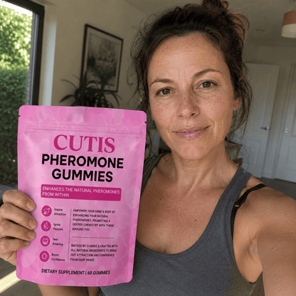 Woman holding a pink package of Cutis Pheromone Gummies in a casual indoor setting.