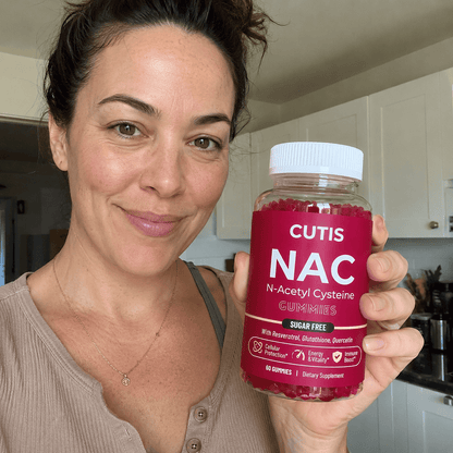 Woman holding a bottle of Cutis NAC gummies in a kitchen.